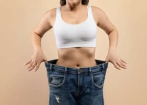 Femme mince au régime en brassière tirant un jean trop grand pour elle