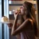 troubles alimentaires Femme mangeant une part de gâteau dans la cuisine, évoquant boulimie et troubles du comportement alimentaire.