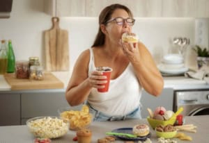 Femme_qui_mange_un_beignet_et_boit_coca_dans_cuisine