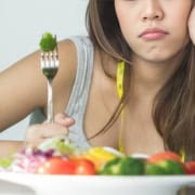 Femme devant assiette de salade au régime drastique et fourchette en l'air