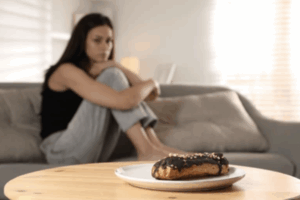 femme au régime qui fait de la boulimie regarde patisserie de loin
