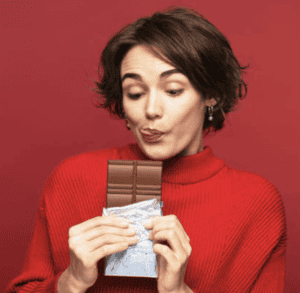 femme en pull rouge mange chocolat 